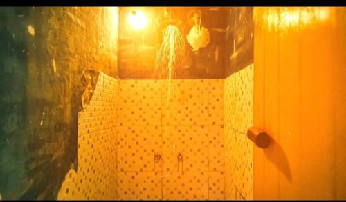 a bathroom with a yellow tiled shower with a light at Deja vu in Barra de Valizas