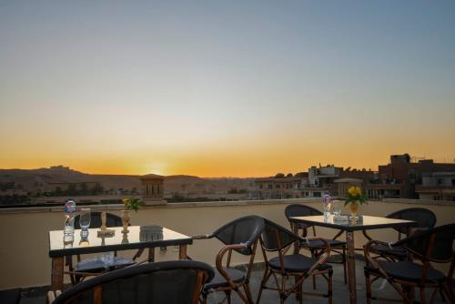King Pyramids View Hotel في القاهرة: طاولتين وكراسي على شرفة مع غروب الشمس