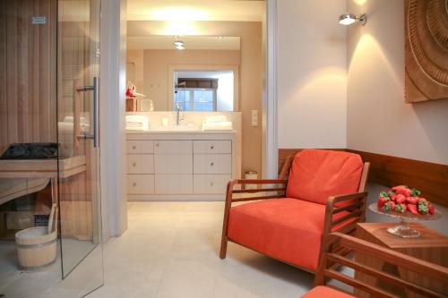 - un salon avec une chaise rouge et un lavabo dans l'établissement NEU Friesenhof Aenne Haus 4 - Ihr friesisches Zuhause unter Reet in Keitum Sylt, à Keitum