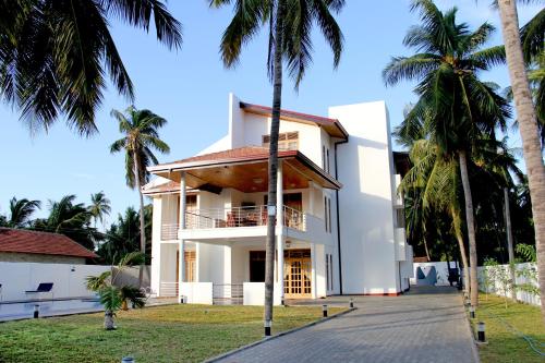 a house with palm trees in front of it at Bluewater Beach Resort in Trincomalee
