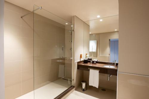 uma casa de banho com um chuveiro, um lavatório e um espelho. em Vila Gale Collection S.Miguel em Ponta Delgada