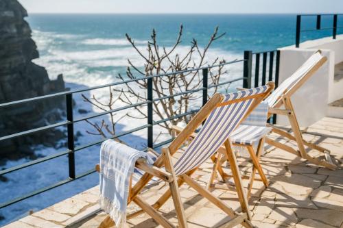 2 sillas sentadas en un balcón con vistas al océano en Casa Condessa - Create memories, en Azenhas do Mar