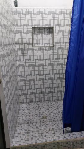 y baño con ducha y pared de azulejos. en Casa de descanso Grace, en Puerto San José
