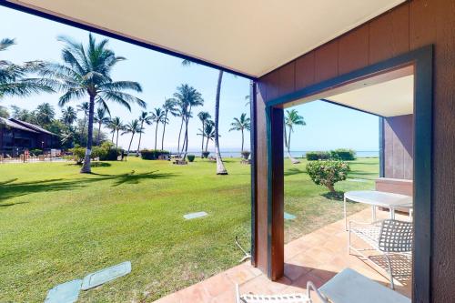 an open door to a patio with a lawn and palm trees at Molokai Shores in Kaunakakai