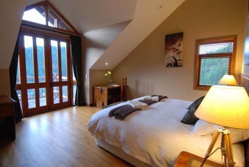 a bedroom with a bed with a lamp and a window at Stonefly Lodge in Stanley Brook