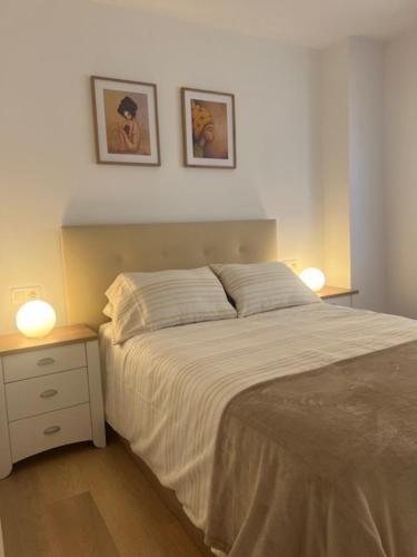 a bedroom with a bed and two pictures on the wall at Piso y parking Zapillo playa in Almería