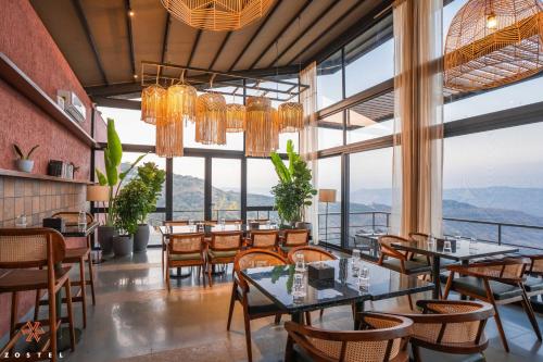 a restaurant with tables and chairs and large windows at Zostel Plus Panchgani in Panchgani
