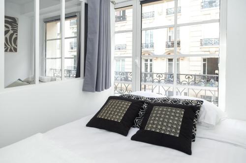 a bedroom with a bed with two pillows and a window at Nets Inn Apartment - Gare de Lyon in Paris