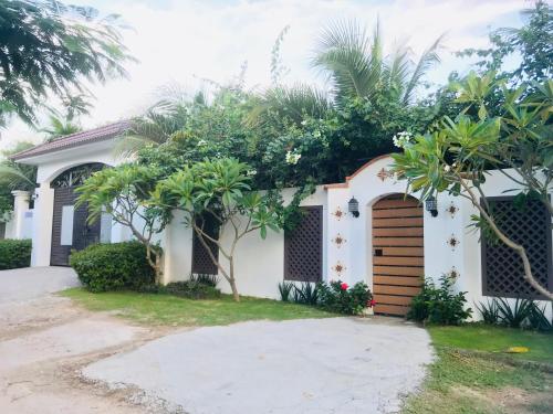 a white house with a brown door and trees at Casa Vi Mia in Ấp Thiện Sơn