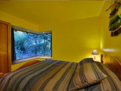 Dormitorio amarillo con cama y ventana en Cabañas Altos del Lago en Pucón