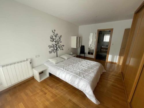 1 dormitorio con cama blanca y suelo de madera en Grupo Gontad Apto Heol Cabana de Bergantiños, en A Coruña