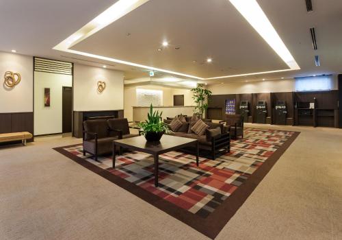 vestíbulo con sala de espera con sofá y mesa en Daiwa Roynet Hotel Oita, en Oita