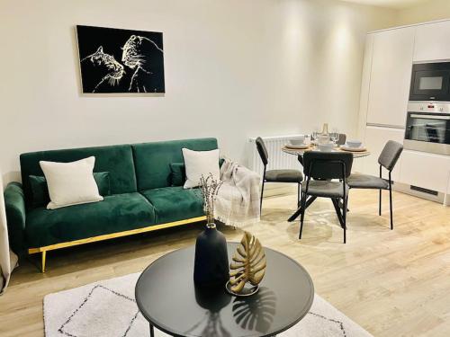 a living room with a green couch and a table at High-Spec Skyline Apartment in London - 2 BDR & Balcony in London