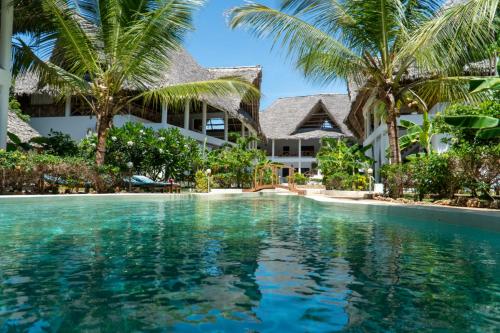 una piscina frente a un edificio con palmeras en Weber Zazu - Maisha Resort, en Watamu