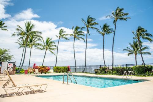 a swimming pool with palm trees and a playground at Molokai Shores in Kaunakakai
