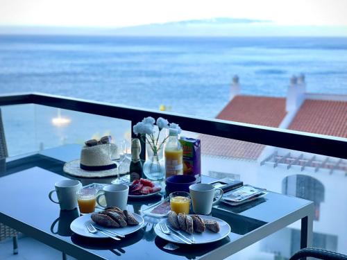 einen Tisch mit Speisen auf einem Balkon mit Meerblick in der Unterkunft Bahia de Santiago in Puerto de Santiago
