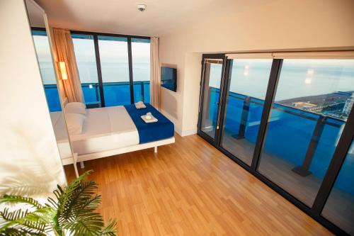 Zimmer mit einem Bett und großen Fenstern in der Unterkunft Panorama Orbi Resort in Batumi