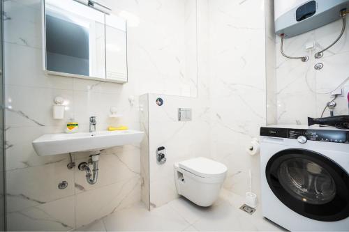 uma casa de banho com uma máquina de lavar roupa ao lado de um WC em Sarajevo Tower 24th floor apartment em Sarajevo