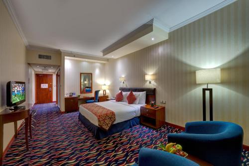ドバイにあるMD Hotel By Gewanのベッドとテレビ付きのホテルルーム