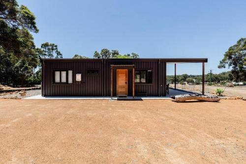a small black house on top of a dirt field at Flame Tree Retreat in Margaret River Town