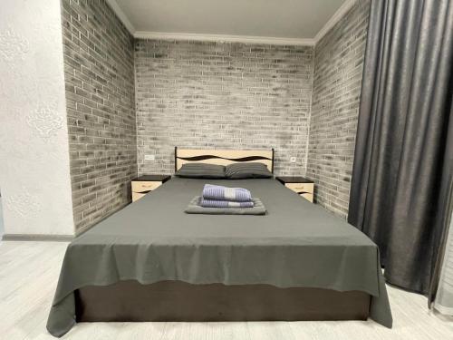 ein Schlafzimmer mit einem Bett mit Ziegelwand in der Unterkunft 1-комнатная квартира в центре города, Букетова 38, Казактелеком. in Petropawlowsk