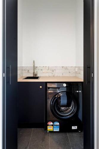 a kitchen with a washing machine under a sink at Flame Tree Retreat in Margaret River Town