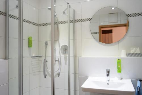 a bathroom with a shower and a sink and a mirror at Hotel Am Freischütz in Hürth