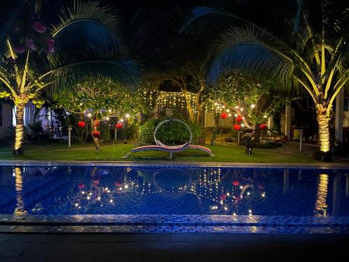 a garden with christmas lights and a swimming pool at Casa Vi Mia in Ấp Thiện Sơn