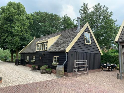 un granero negro con techo de gambrel en Op Stolk bed & breakfast, en Stolwijk