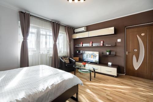 a bedroom with a bed and a table and a tv at Studio 37 by MRG Apartments in Bucharest