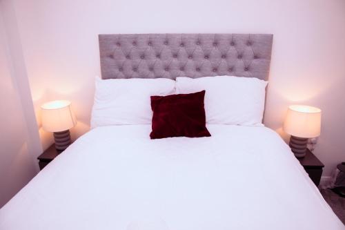 1 dormitorio con cama blanca grande y almohada roja en City Centre Luxury Apartment, en Belfast