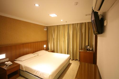 a hotel room with a bed and a television at Cardogan Hotel in Kuala Lumpur