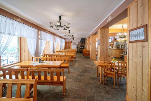 a restaurant with wooden tables and wooden chairs at Zajazd Górski Kuźnice in Zakopane