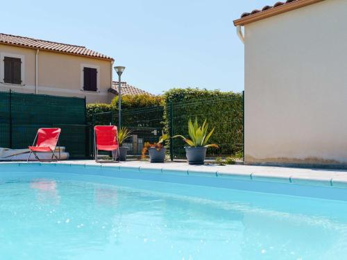 une piscine avec deux chaises rouges et des plantes dans l'établissement Villa 4 pièces avec piscine privée, jardin, garage, 7 couchages, Narbonne-Plage, proche commerces - FR-1-409-21, à Narbonne
