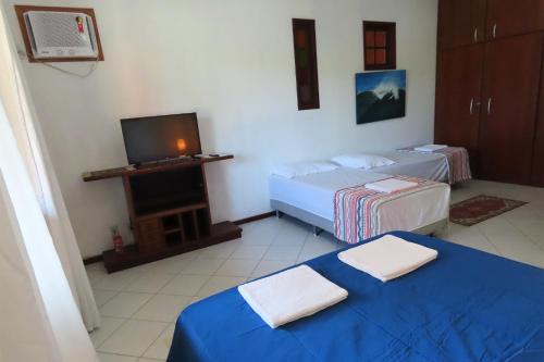 a hotel room with two beds and a television at Casa Flora in Cabo Frio