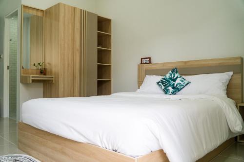 a bedroom with a large white bed with a wooden headboard at เมตตา เรสซิเด้นซ์ - Metta Residence in Ban Dam Phra