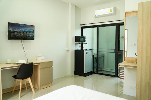 Ban Dam Phraにあるเมตตา เรสซิเด้นซ์ - Metta Residenceの冷蔵庫、デスク、椅子が備わる客室です。