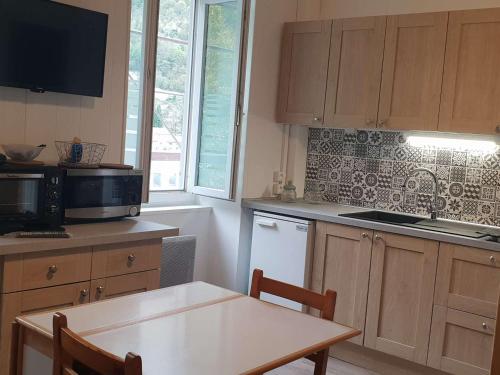 une cuisine avec une petite table et un micro-ondes dans l'établissement Studio rénové pour 4 pers à 50m du télécabine - FR-1-234-293, à Cauterets