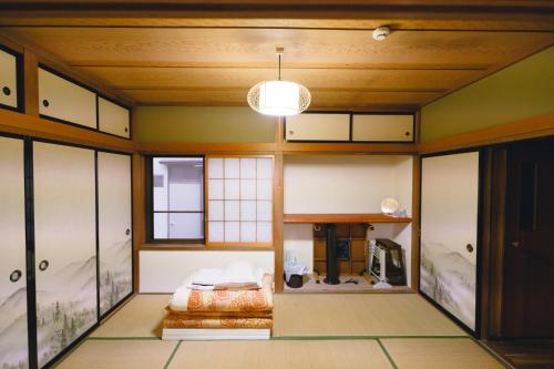 Zimmer mit einem Bett in einem Zimmer mit Fenstern in der Unterkunft 八戸ゲストハウス トセノイエ / Hachinohe Guest House Tosenoie in Hachinohe