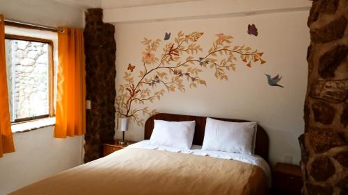 a bedroom with a bed with a bird mural on the wall at Casa Inka B&B in Ollantaytambo