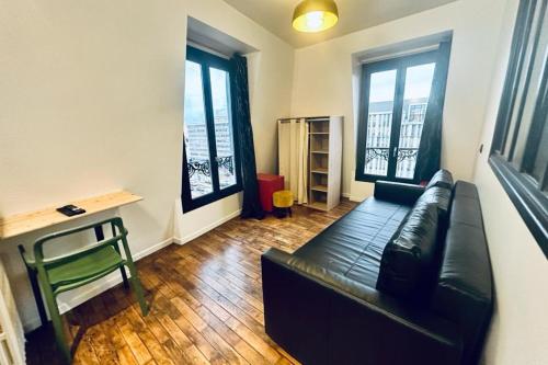 sala de estar con sofá de cuero negro y 2 ventanas en Attractive 20 m in the heart of city en Neuilly-sur-Seine