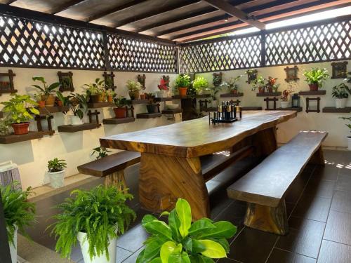 uma grande mesa de madeira e bancos numa sala com vasos de plantas em Aika Homestay em Shah Alam