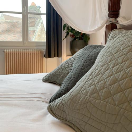 an unmade bed in a bedroom with a window at Appartements 4 vents by La Boîte En Plus in Senlis