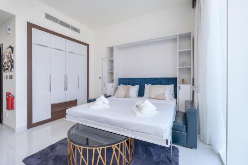 a bedroom with a large bed with a blue headboard at Placid Studio close to Dubai Miracle Garden in Dubai