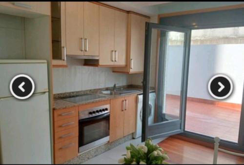 una cocina con armarios de madera y una puerta corredera de cristal en Apartamento en Pontevedra con terraza y garaje en Poio