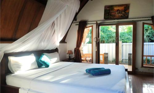 ein Schlafzimmer mit einem großen weißen Bett mit blauen Kissen in der Unterkunft Matahari Bungalow 3 in Gili Air
