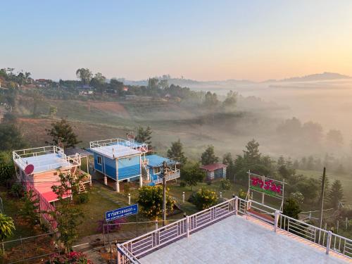 Vista arial de uma colina enevoada com casas numa colina em Charmtalamok Khaokho Resort em Ban Khao Ya Nua