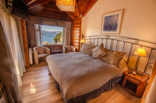 a bedroom with a bed and a large window at Nido del Cóndor Hotel & Spa in San Carlos de Bariloche