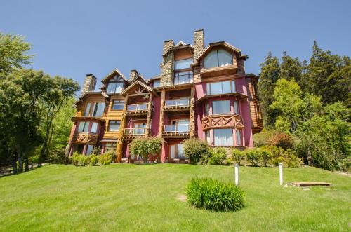 una casa grande en la cima de un campo verde en Nido del Cóndor Hotel & Spa en San Carlos de Bariloche