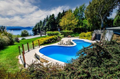 una piscina en un patio junto a un lago en Nido del Cóndor Hotel & Spa en San Carlos de Bariloche